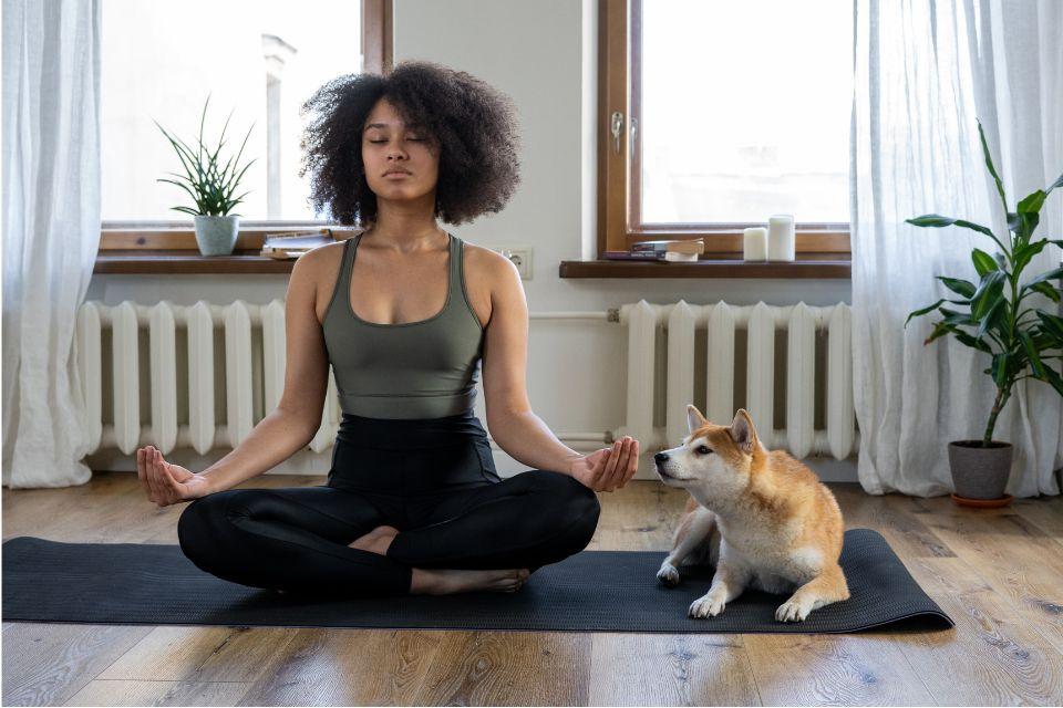 A meditating woman sitting cross-legged on a yoga mat with her eyes closed