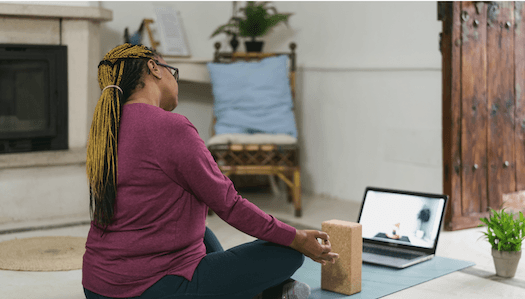 Woman on a yoga mat facing a laptop