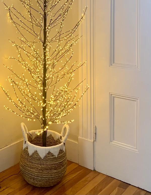Small lighted tree in corner of a yellow room