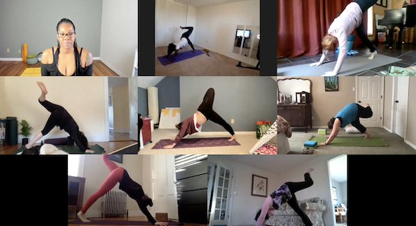 Chanel Sledge, smiling in a meditation pose with prayer hands in front of a mural