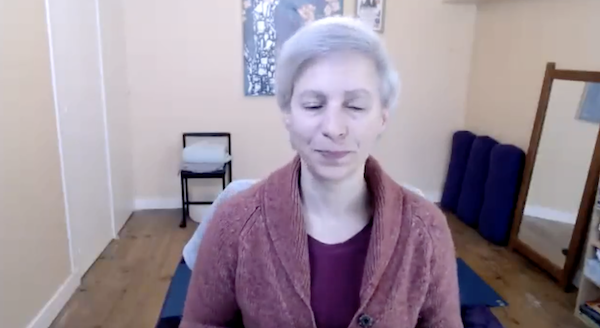 Ompractice teacher Beth Ciesco seated in meditation on a cliff