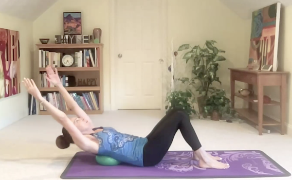 Ompractice teacher Jayne Schmitz doing Pilates teaser on Pilates mat on grass