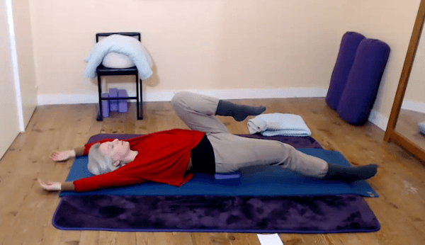 Ompractice teacher Beth Ciesco lying on a mat stretching