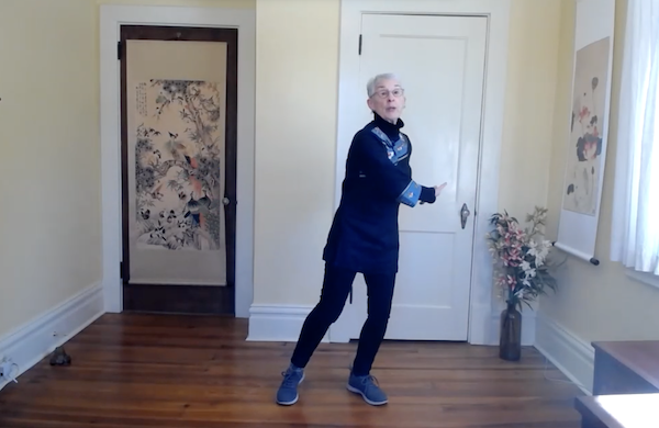 Gurney Bolster, practicing Tai Chi on a boulder with the sky behind her
