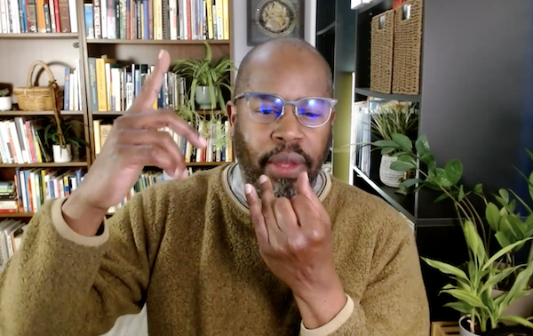 Ompractice Teacher Eric demonstrates the beginning of a breathwork post with his hand lifted towards his face