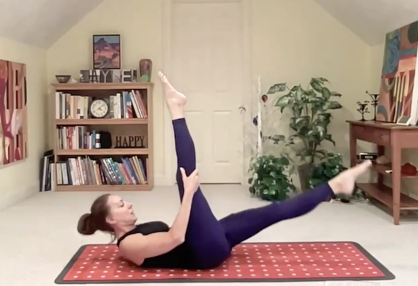 Ompractice teacher Jayne Brown lying on her back with her leg raised to the sky