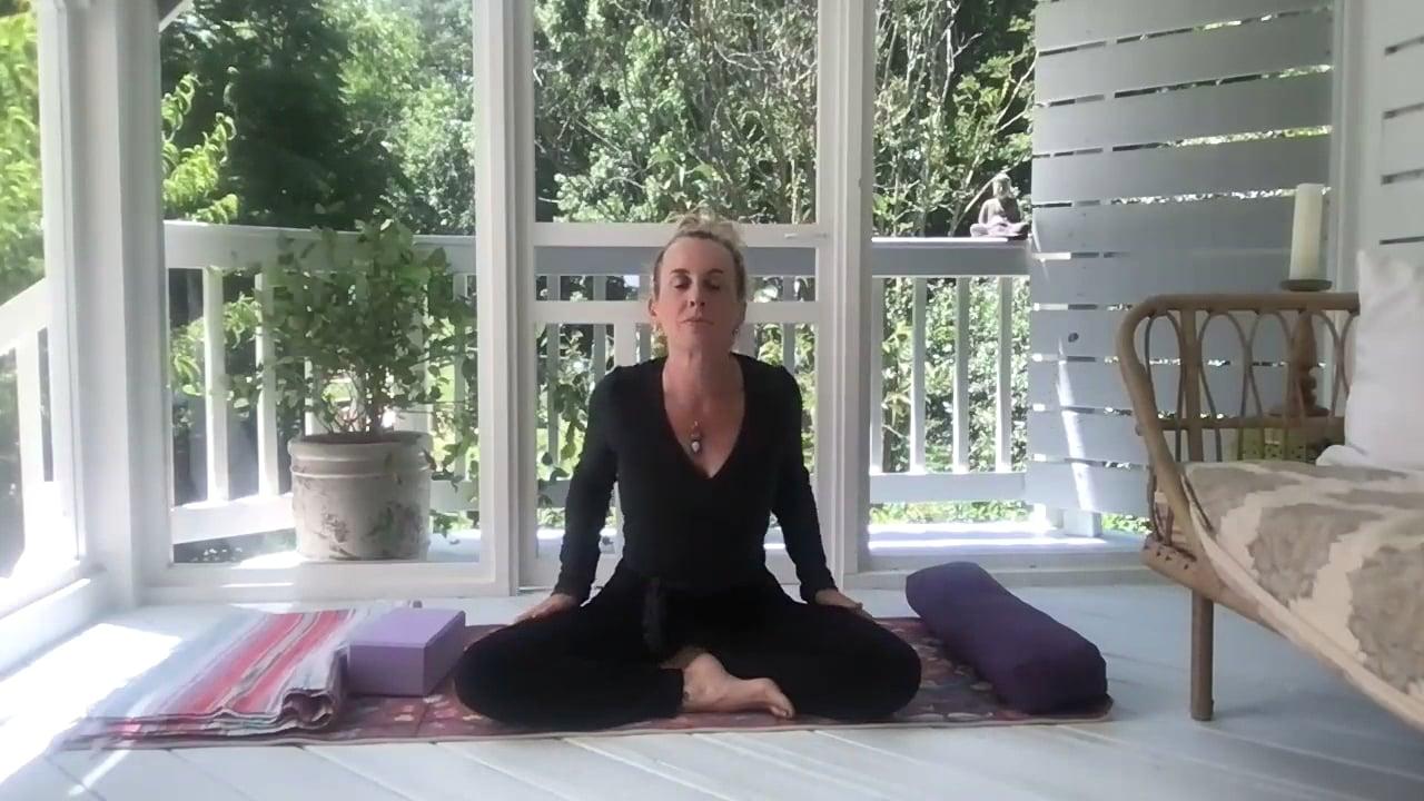 Ompractice teacher Prema Posner seated crosslegged on her mat