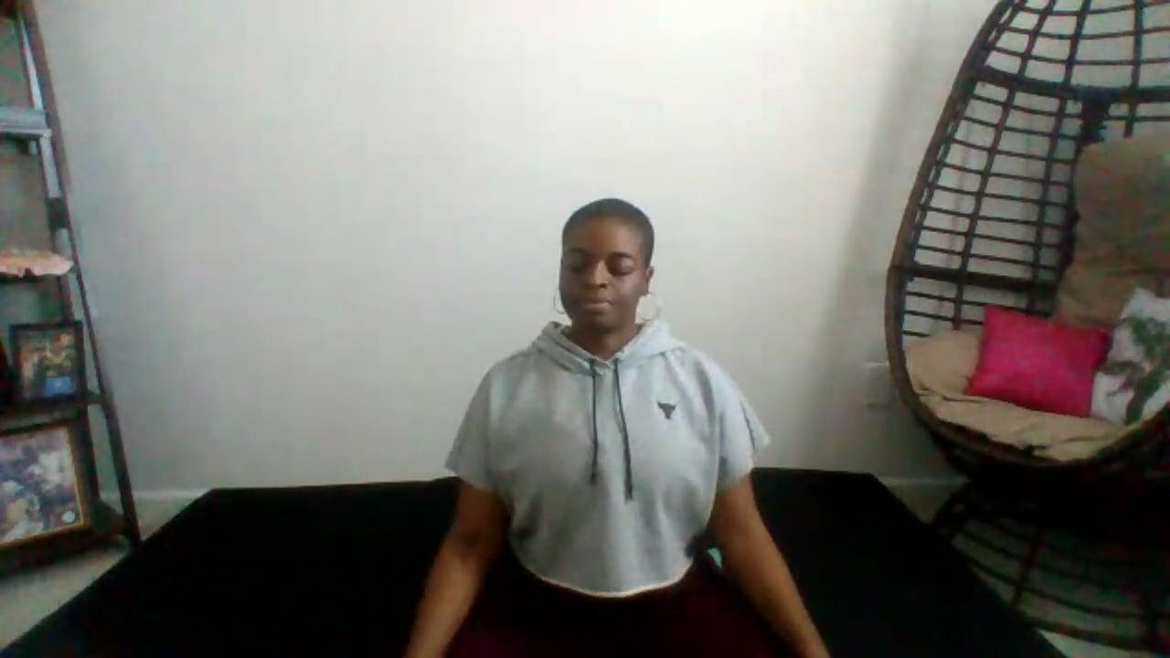 Ompractice teacher Alynthia Penn seated with her eyes closed in a grey sweatshirt