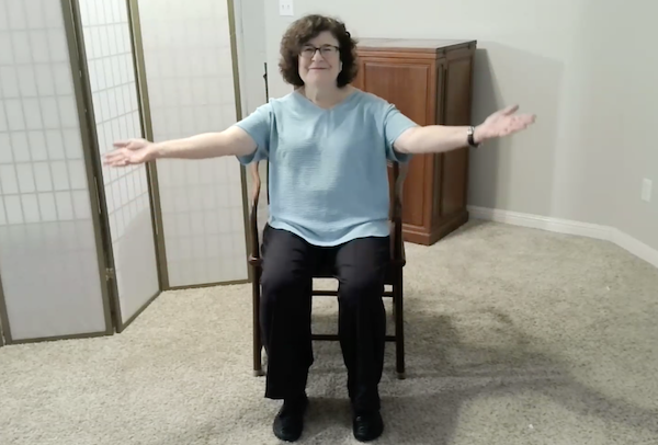 Ompractice teacher Patricia Lawson teaching seated tai chi with arms raised wide open