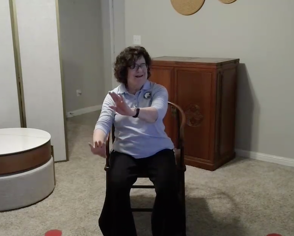 Ompractice teacher Patricia Lawson teaching seated tai chi with arms extended forward