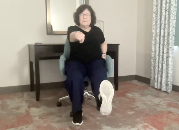 Ompractice teacher Patricia Lawson teaching seated tai chi kicking her foot forward