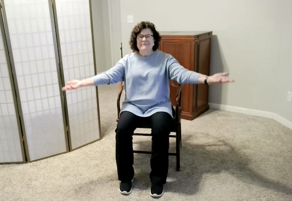 Ompractice teacher Patricia Lawson teaching seated tai chi with arms extended wide