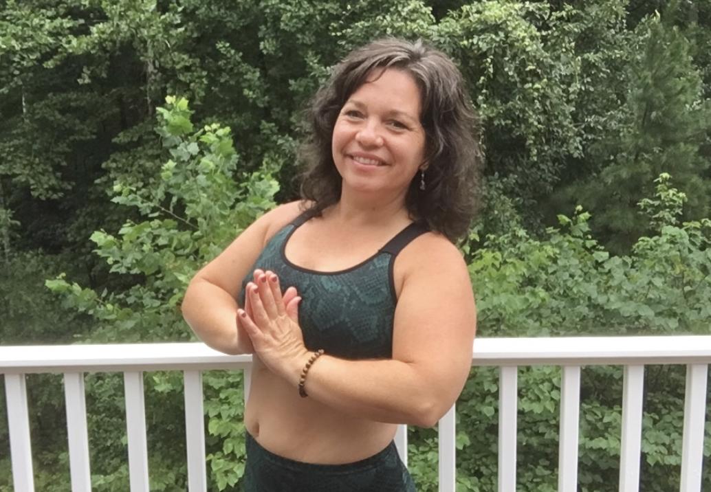 Traci Ayers, with her hands in a prayer position in front of trees