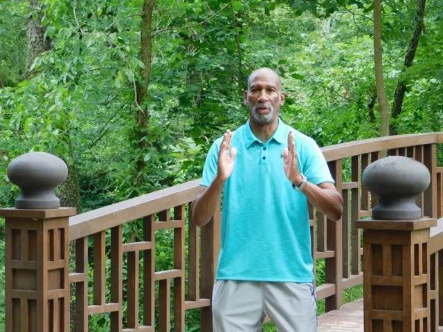 Ompractice teacher Sharif Zyhier doing Tai Chi on bridge with trees in background