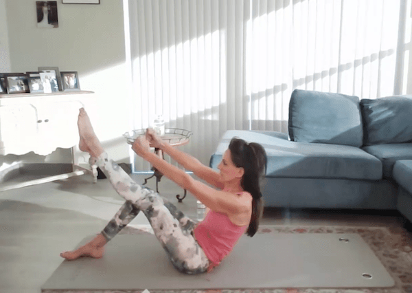 Ompractice Teacher Barb Hospod on mat doing a pilates move